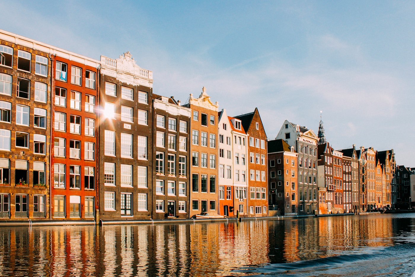 Amsterdam canal houses lit gold, reflected in the water