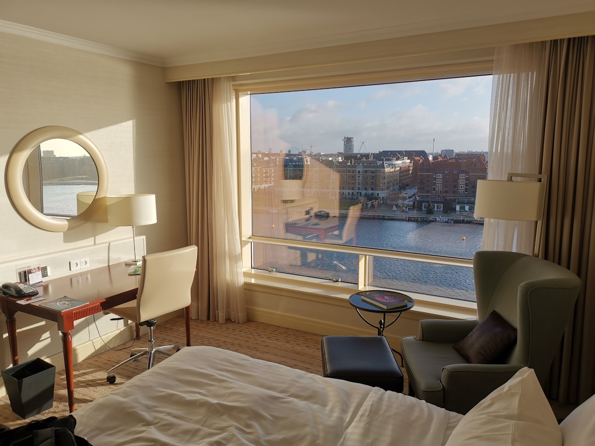 A made bed beside a wide window in a bright cabin