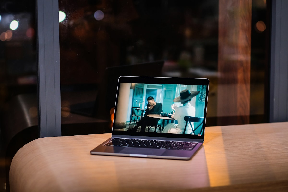 An open laptop on a wooden table playing a video
