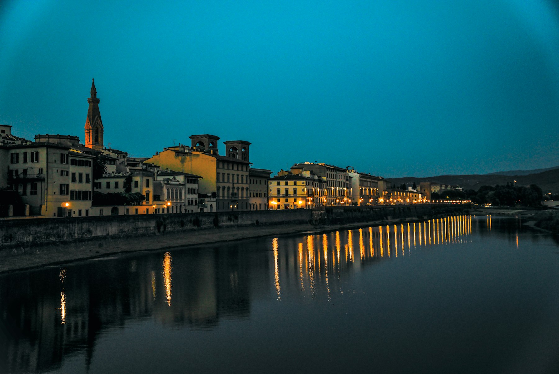 A river town at dusk with lights reflected on the water