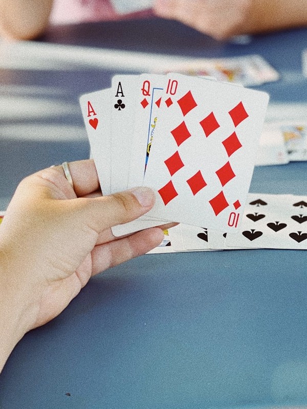 A hand of playing cards held above a table mid-game