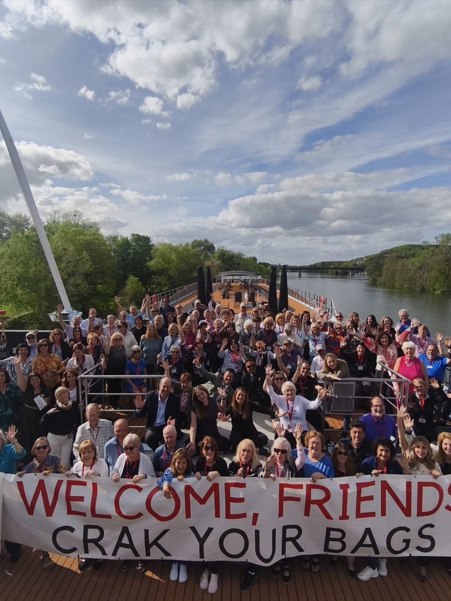 The whole group on the sun deck behind a Welcome Friends banner